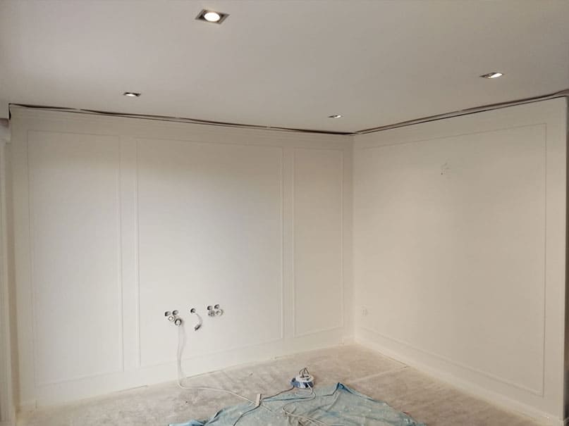Panelado renovado con molduras y lacado blanco para una pared elegante y luminosa